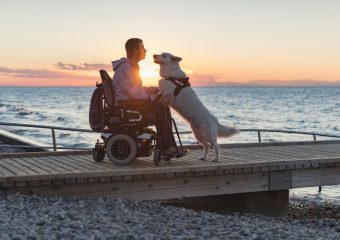 Man in power wheelchair with dog on beach