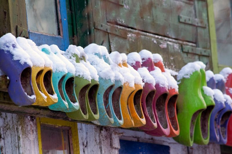 Photograph of colourful Clogs on a wall in Amsterdam covered in snow
